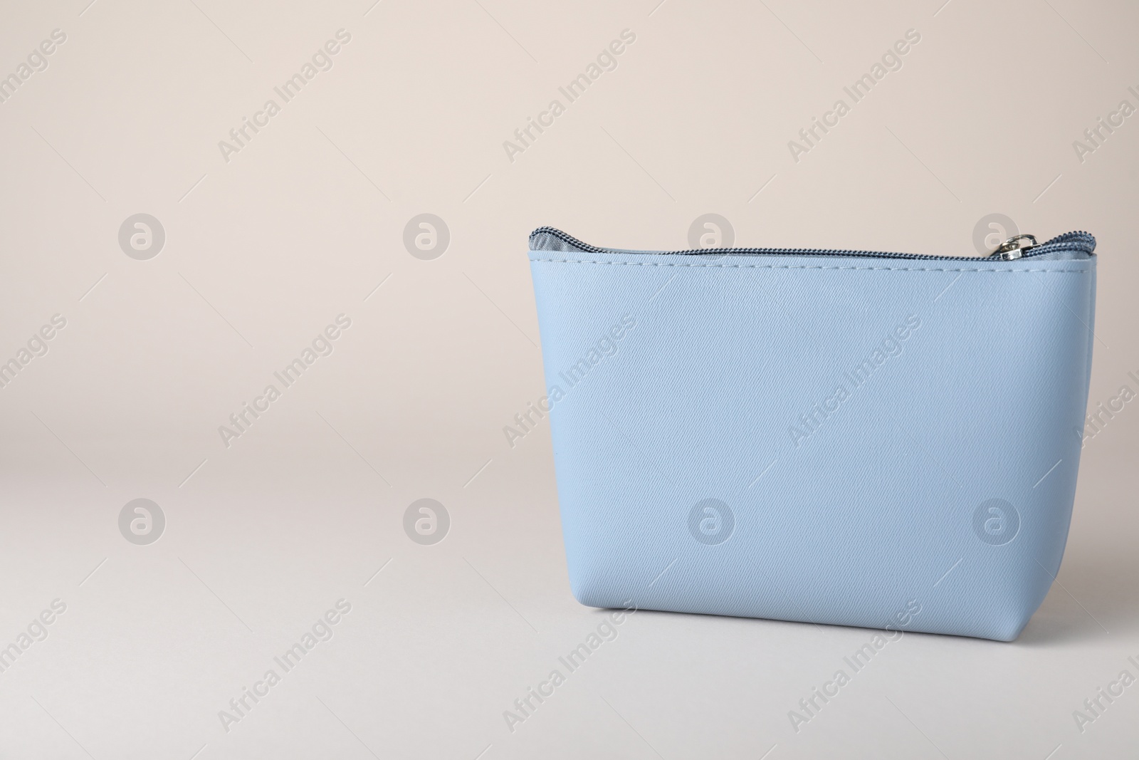 Photo of Light blue cosmetic bag on beige background. Space for text