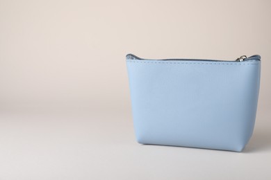 Light blue cosmetic bag on beige background. Space for text