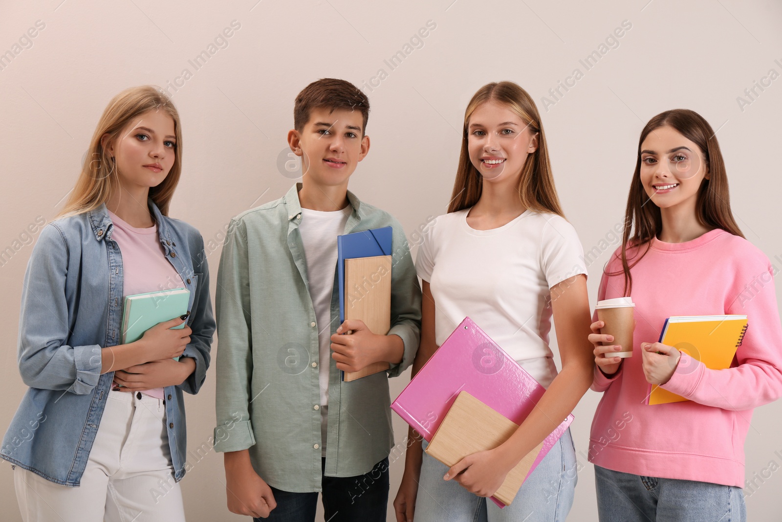 Photo of Group of teenage students with stationery on beige background