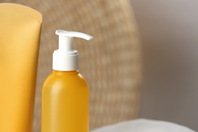 Bottle and tube of face cleansing products on blurred background, closeup. Space for text