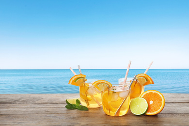 Image of Tasty refreshing drink on wooden table against sea