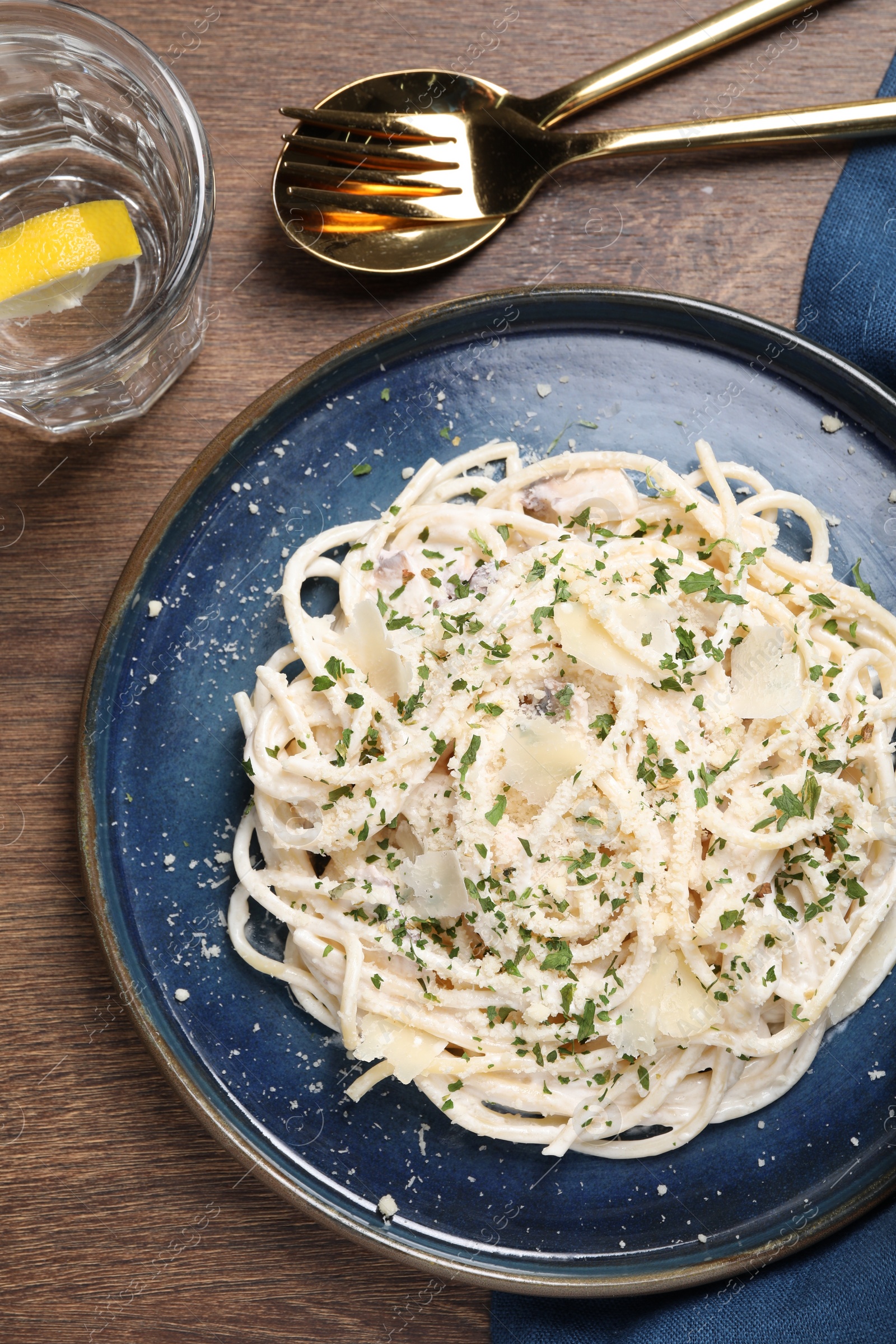 Photo of Delicious pasta with mushroom sauce and parmesan cheese served on wooden table, flat lay