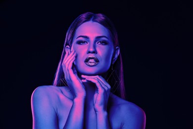 Portrait of beautiful woman posing in neon lights against black background