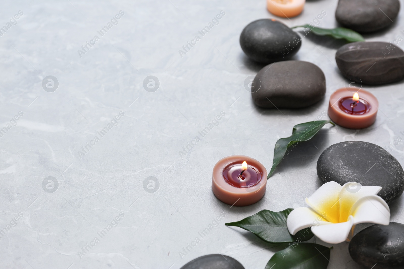 Photo of Composition with spa stones and lit candles on grey marble background, space for text