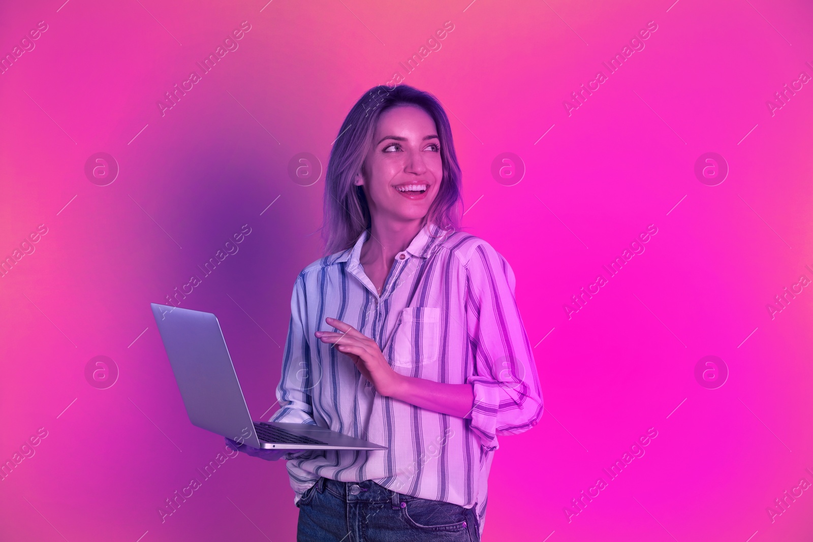 Image of Beautiful woman with laptop in neon lights