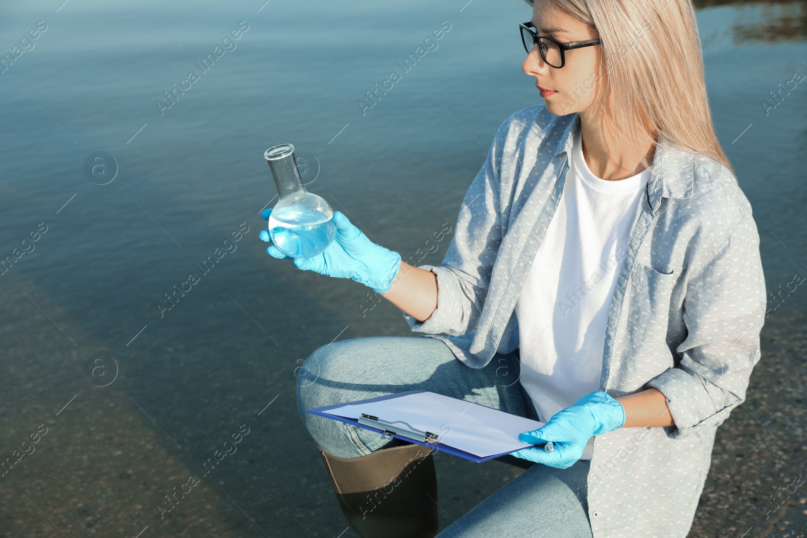 Photo of Scientist with clipboard and sample taken from river