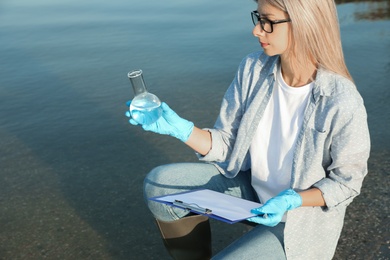 Scientist with clipboard and sample taken from river