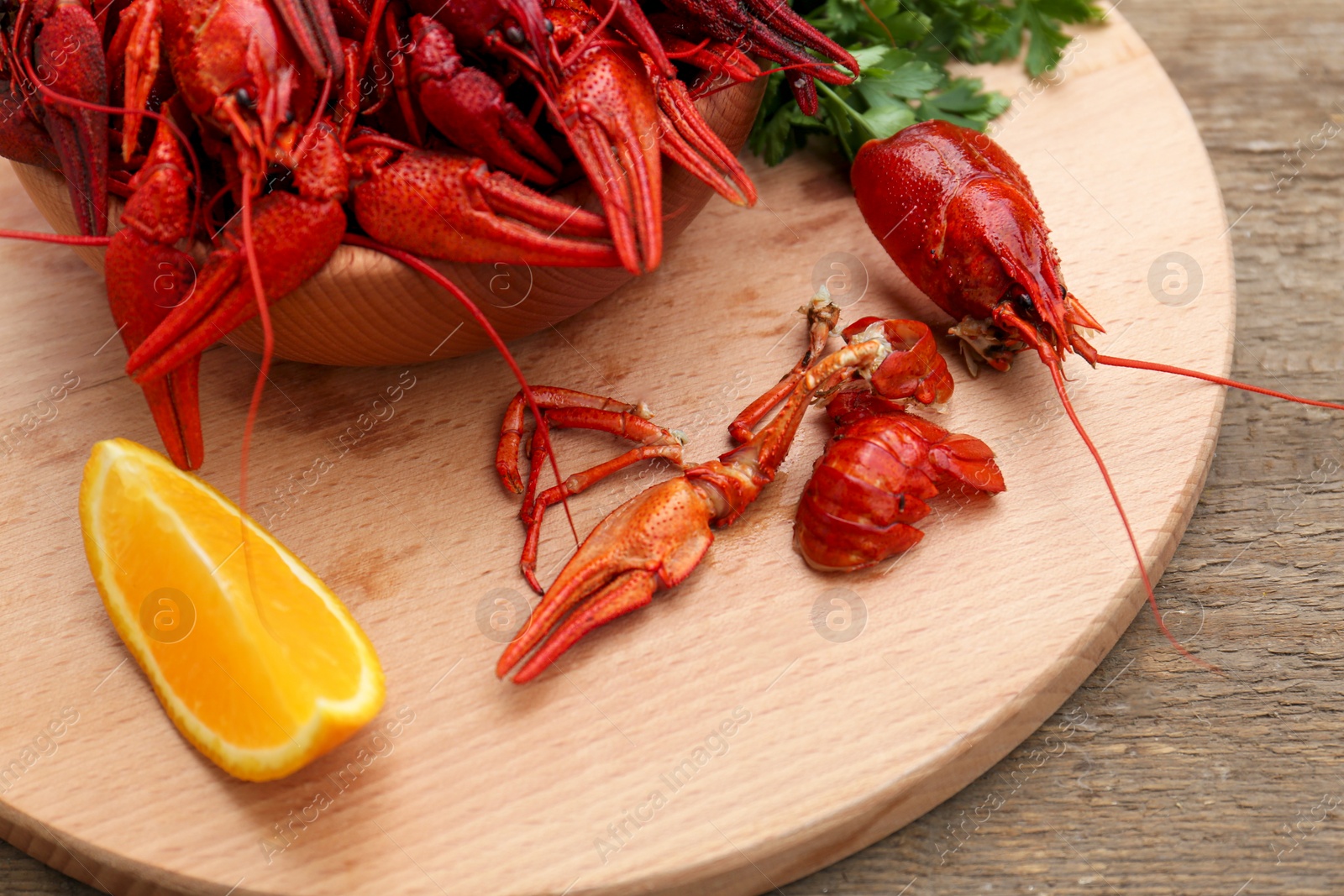 Photo of Delicious red boiled crayfish and orange on wooden table