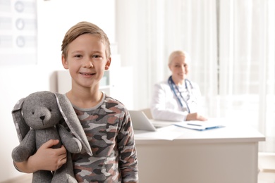 Photo of Adorable child with toy visiting doctor at hospital