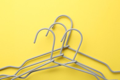 Photo of Many hangers on yellow background, top view