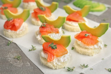 Photo of Tasty sandwiches with fresh sliced salmon fillet and avocado on table, closeup