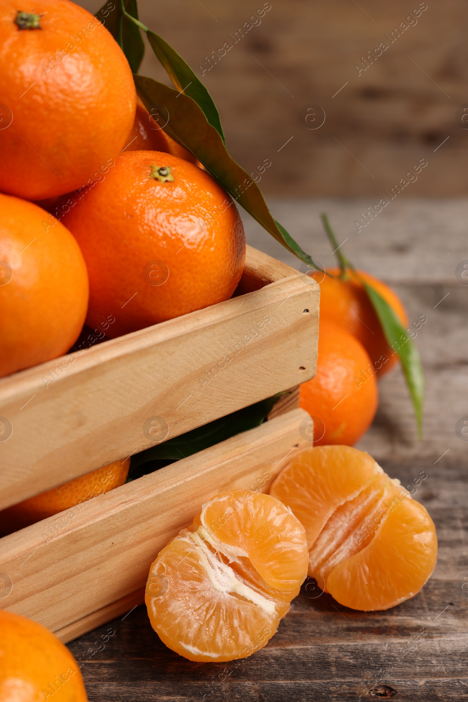 Photo of Delicious tangerines with leaves on wooden table, closeup