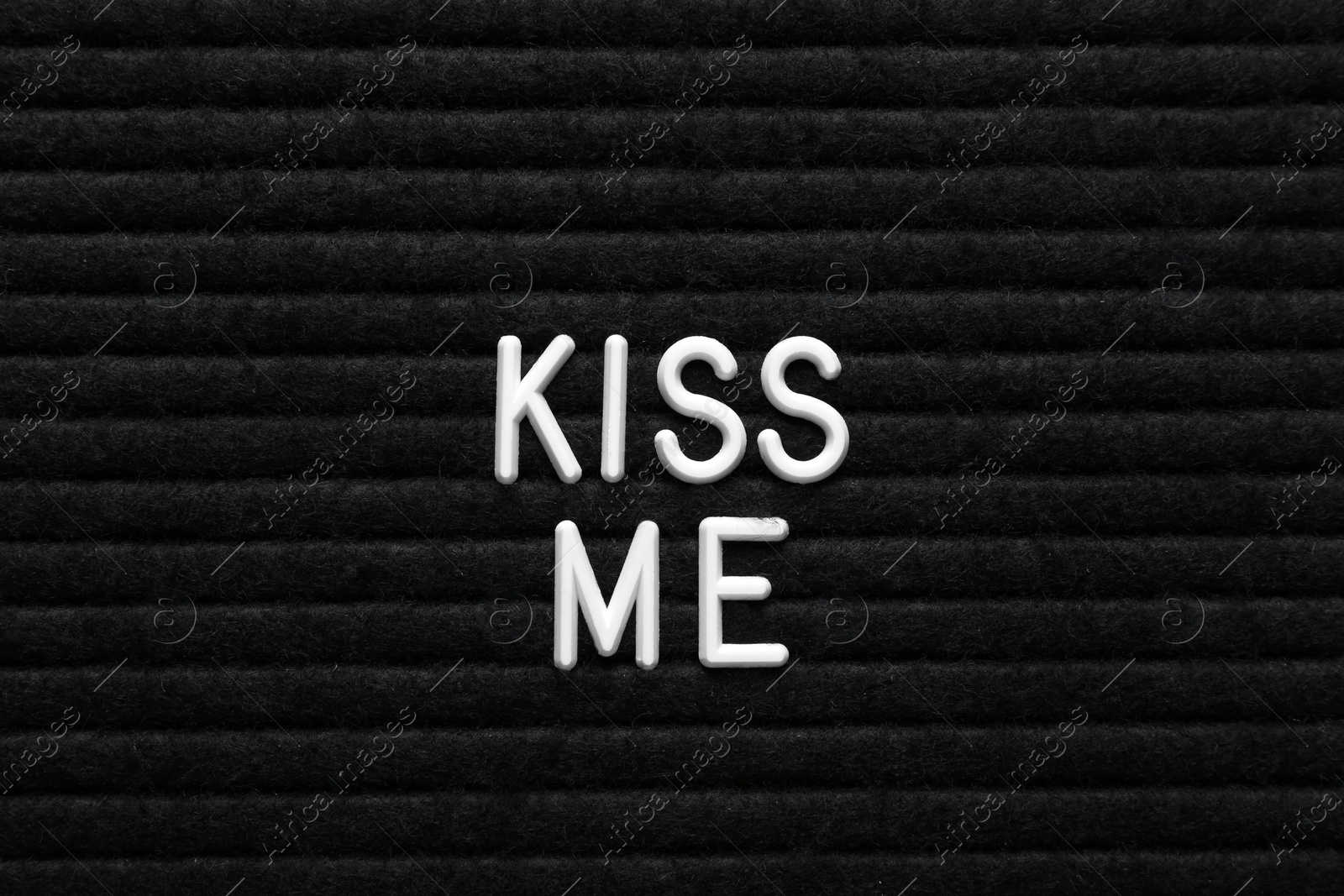 Photo of Phrase Kiss Me on black textured surface