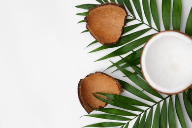 Photo of Fresh coconut and palm leaves on white background, top view