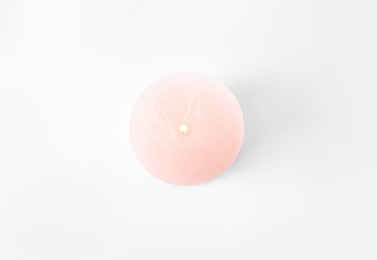 Photo of Burning pink candle isolated on white, top view
