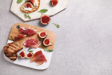 Delicious ripe figs, prosciutto and toasted bread served on light table, top view. Space for text