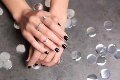 Woman showing black manicure on grey background, closeup with space for text. Nail polish trends