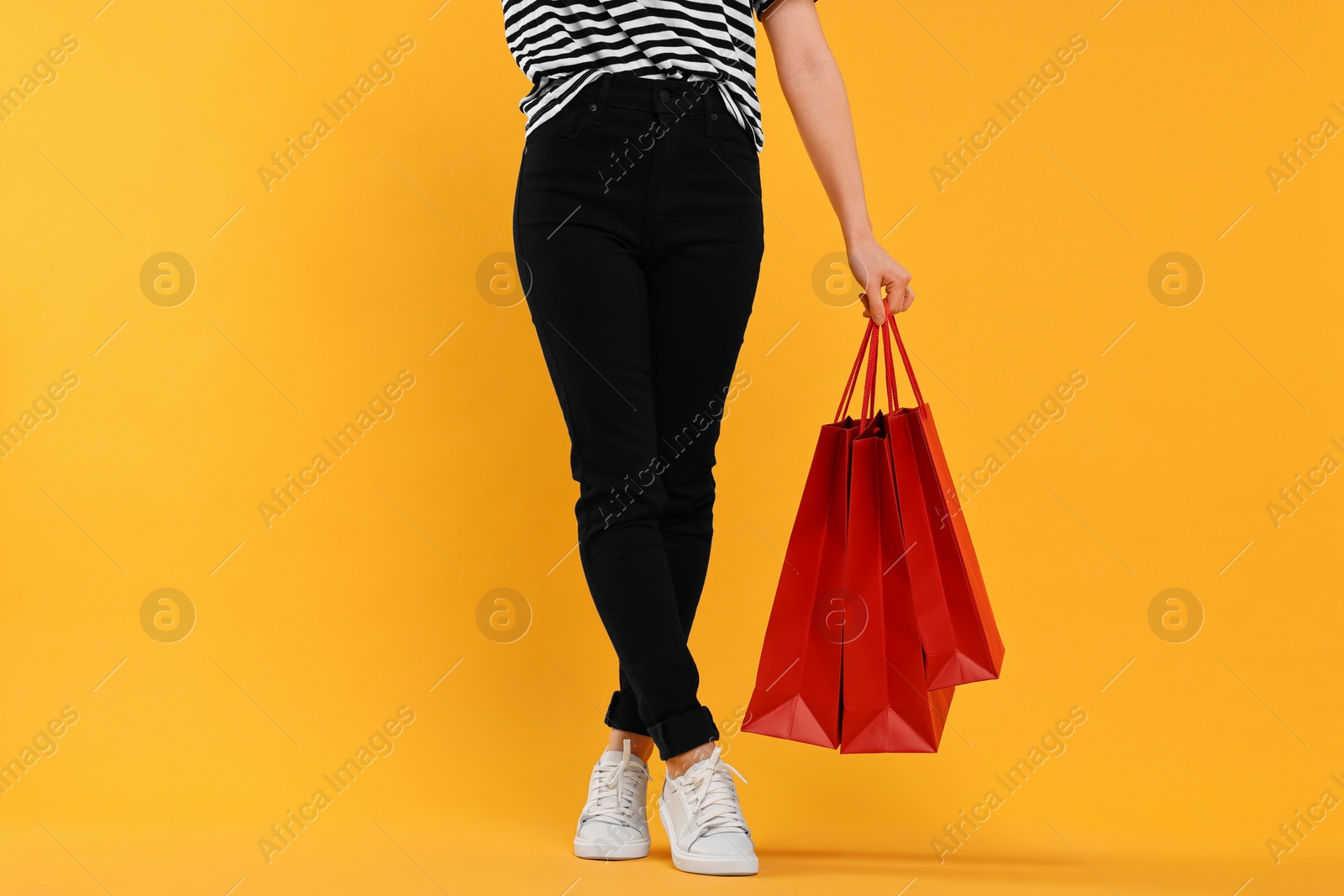 Photo of Woman with shopping bags on yellow background, closeup