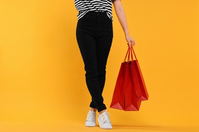 Photo of Woman with shopping bags on yellow background, closeup
