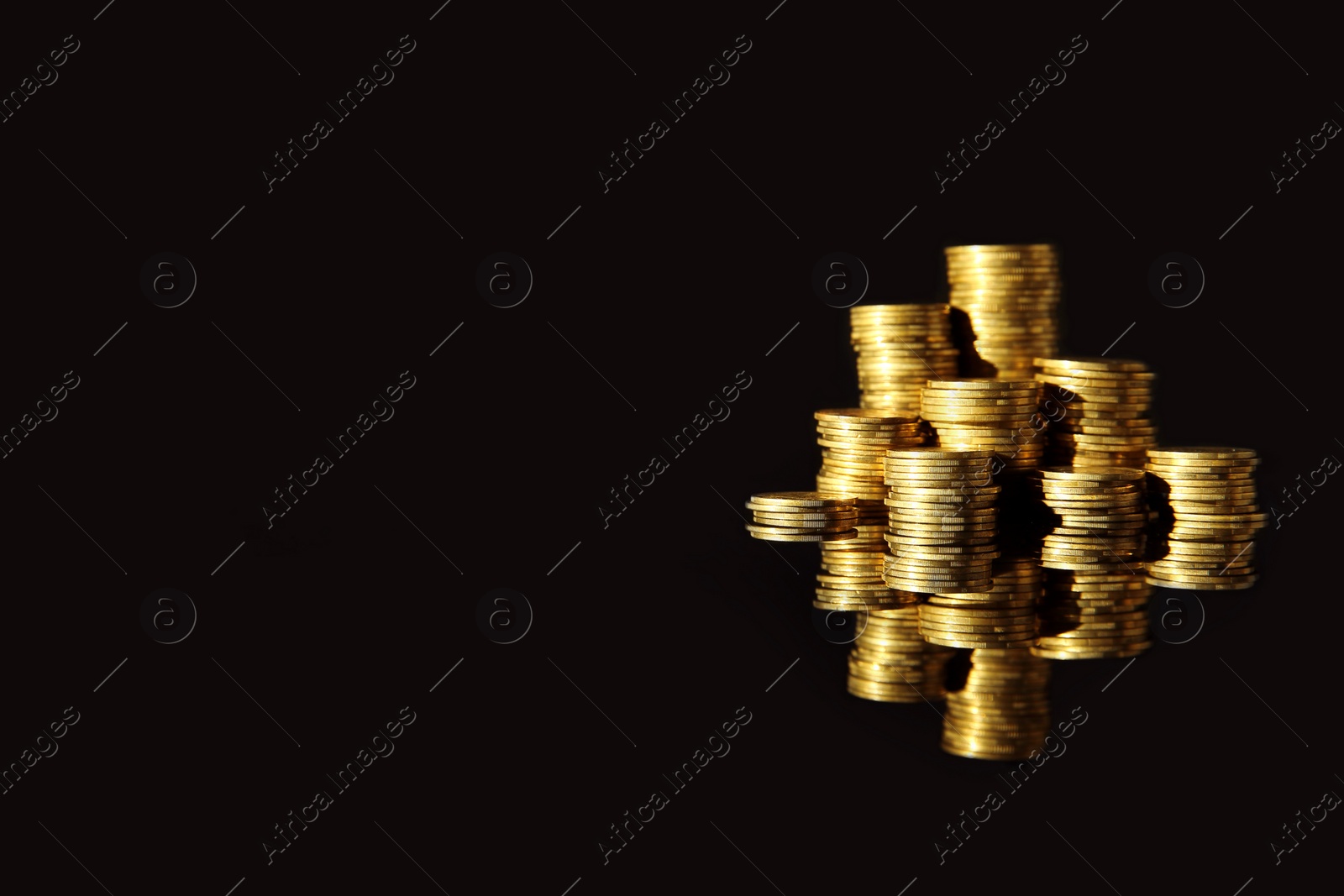 Photo of Many stacks of coins on mirror surface against black background, space for text