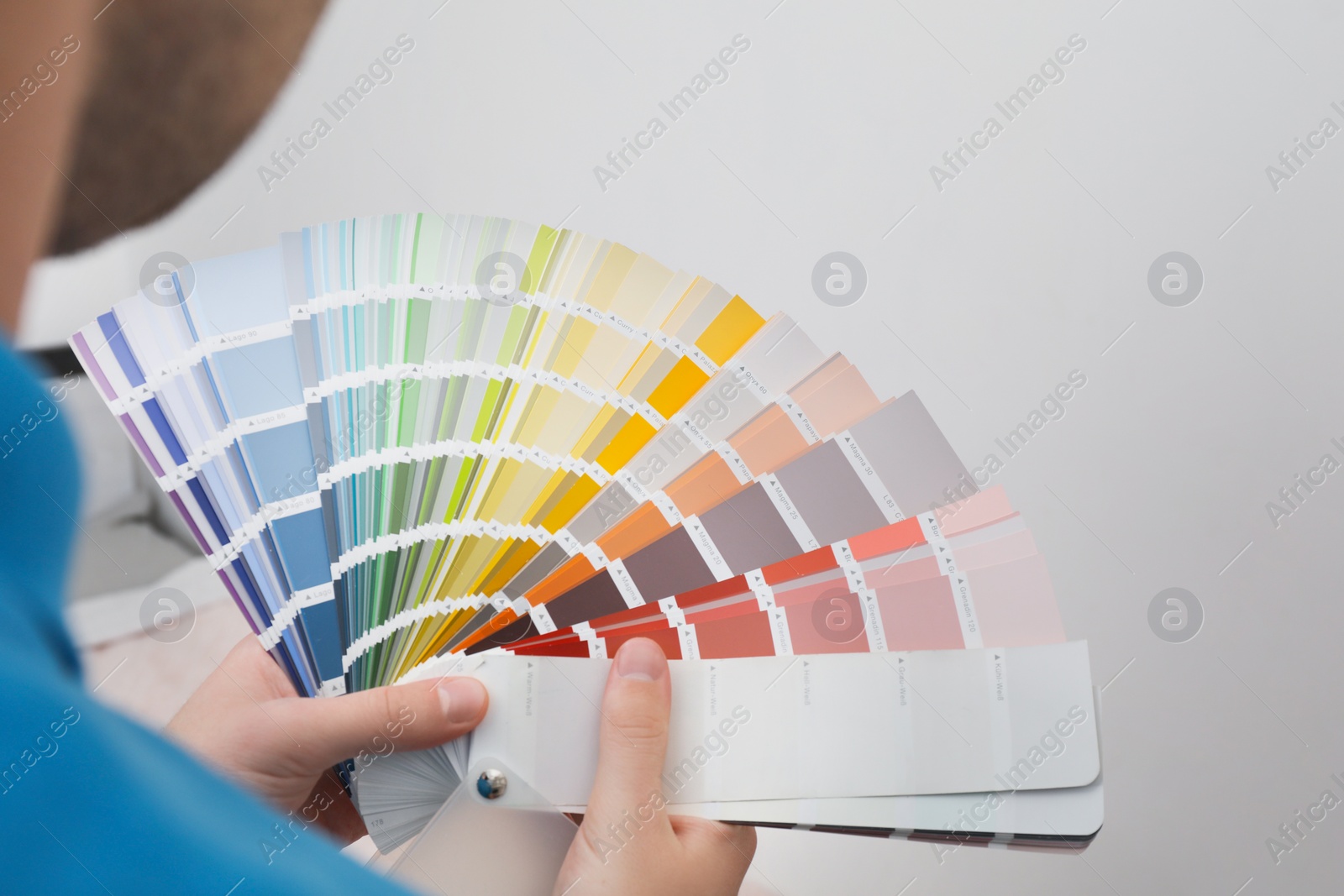 Photo of Man with palette choosing color for painting wall indoors, closeup. Interior design