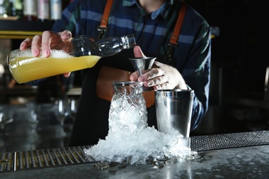 Photo of Barman making tropical cocktail at counter in pub, closeup
