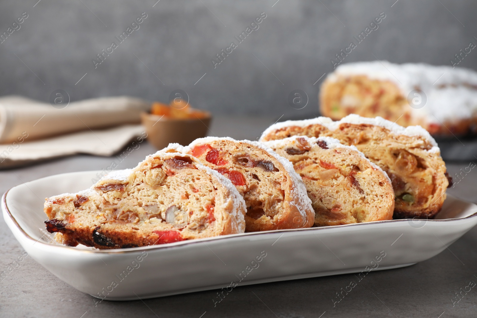 Photo of Traditional Christmas Stollen with icing sugar on grey table