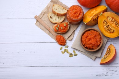 Delicious pumpkin jam and fresh pumpkin on white wooden table, flat lay. Space for text