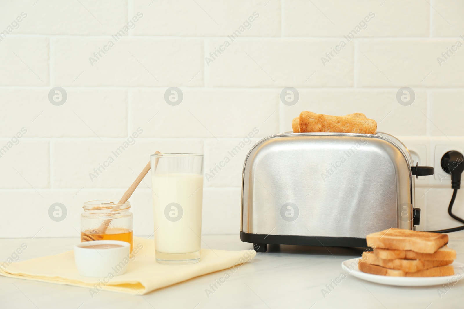 Photo of Modern toaster and tasty breakfast on counter in kitchen