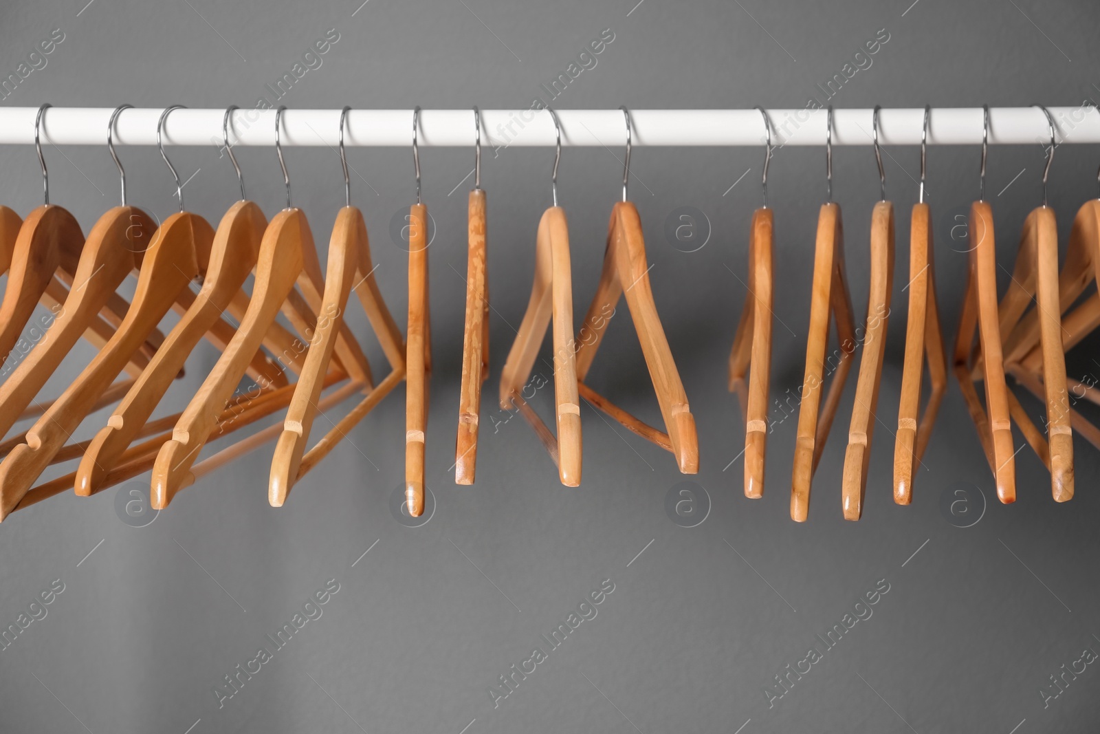 Photo of Clothes rail with wooden hangers on gray background