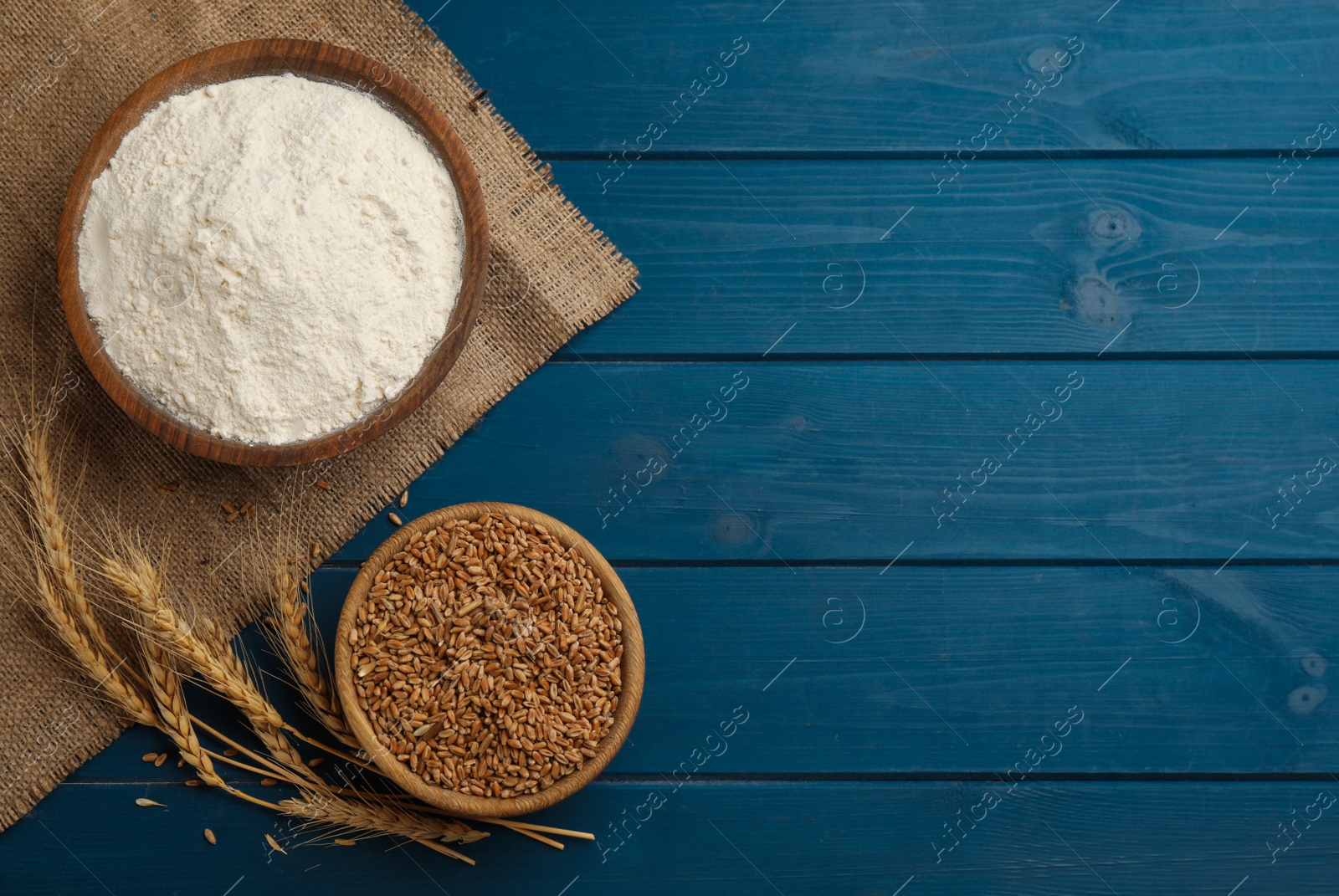 Photo of Flat lay composition with wheat flour on blue wooden table. Space for text