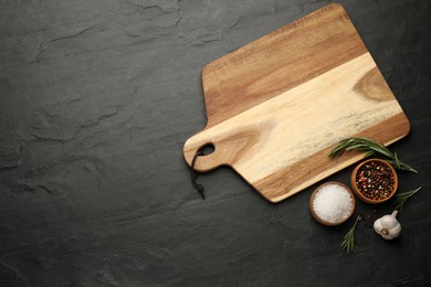 Photo of Flat lay composition with wooden cutting board and ingredients on black table, space for text. Cooking utensil