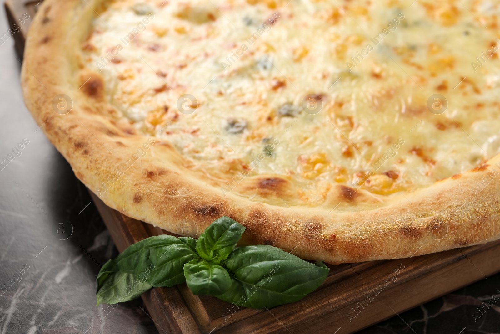 Photo of Delicious cheese pizza and basil on black marble table, closeup