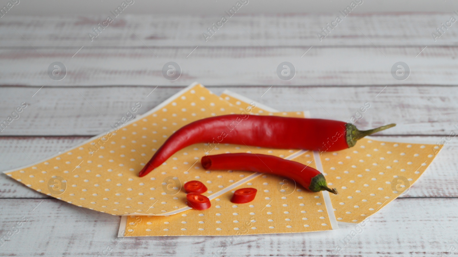 Photo of Many pepper plasters and chili on white wooden table, closeup