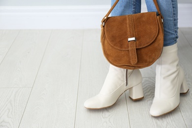 Woman in stylish leather shoes with bag indoors, closeup. Space for text