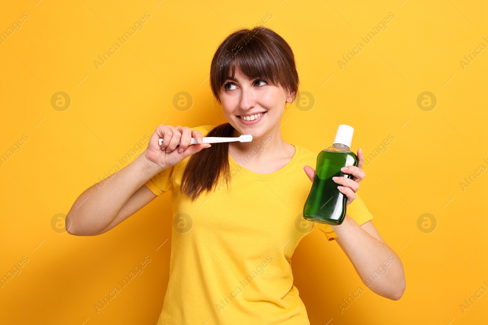 Photo of Young woman with mouthwash and toothbrush on yellow background