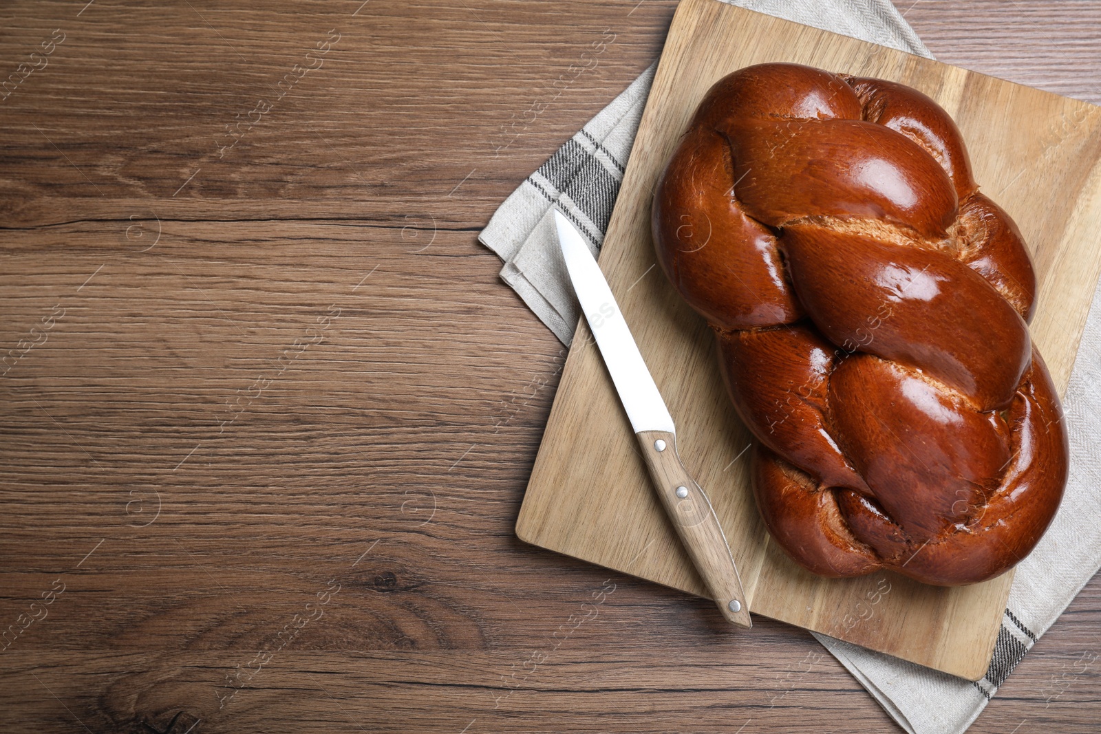 Photo of Homemade braided bread on wooden table, top view and space for text. Traditional Shabbat challah