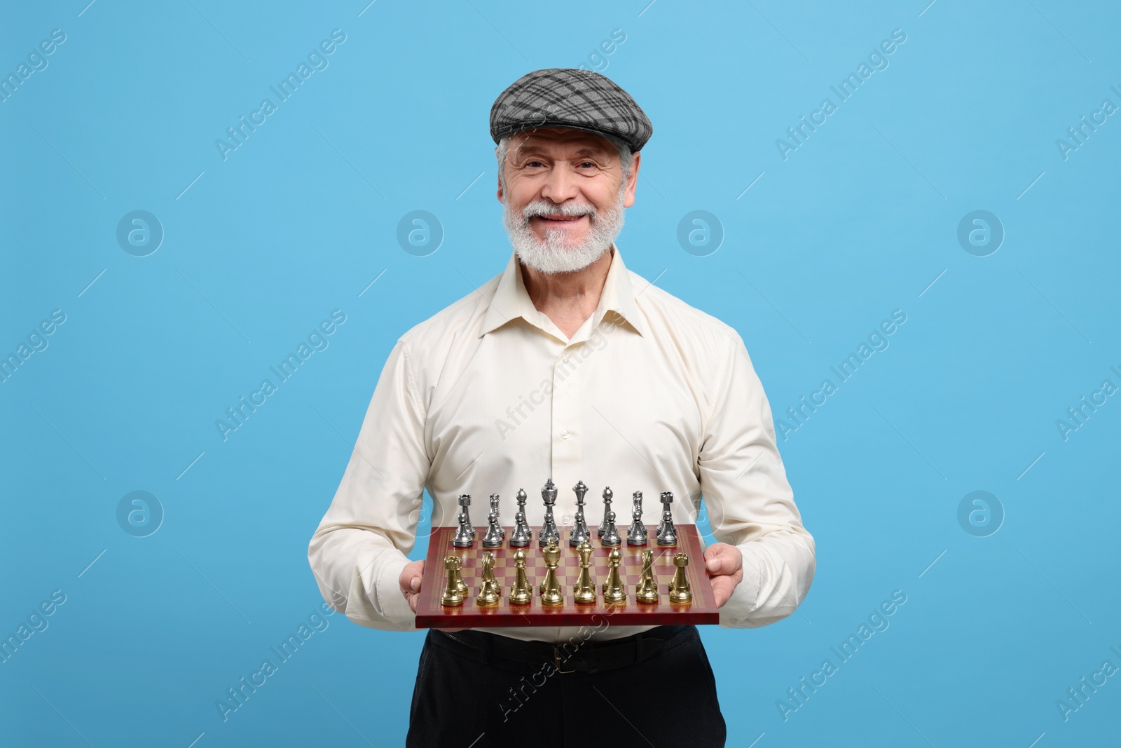 Photo of Man with chessboard and game pieces on light blue background