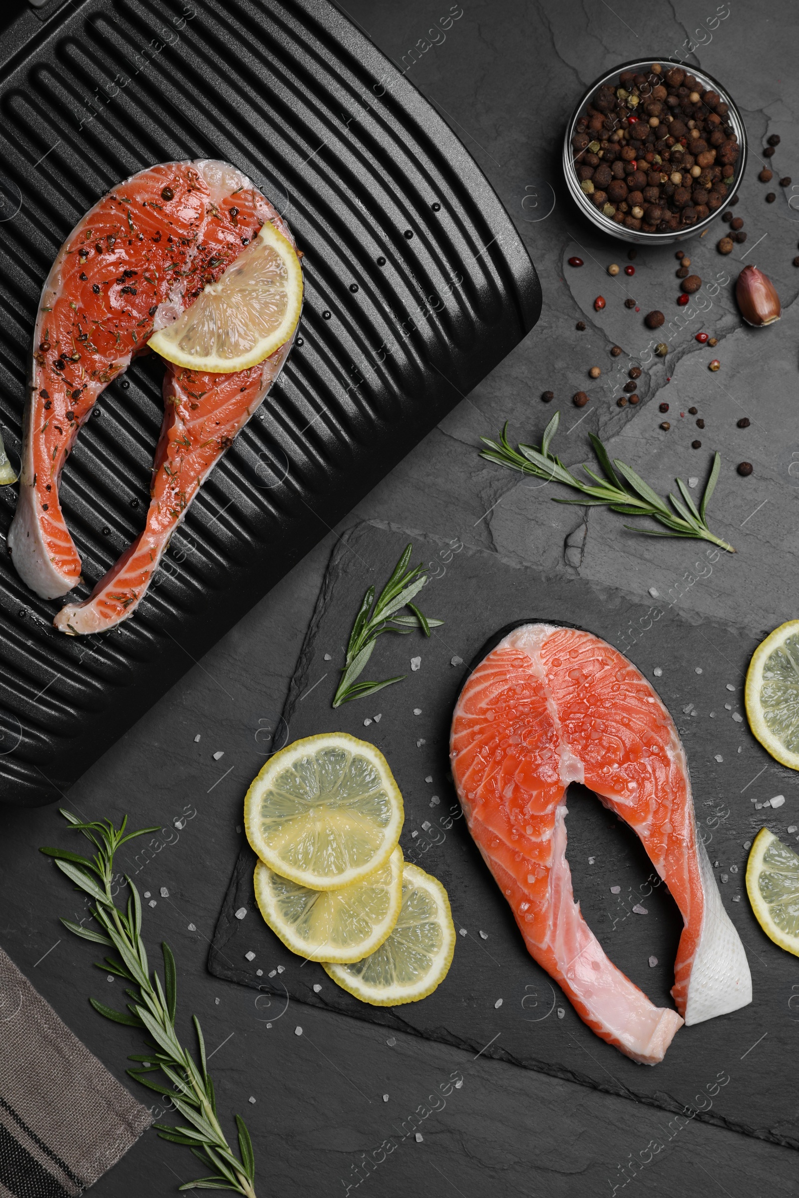 Photo of Cooking salmon. Grill, fresh fish steaks, lemon and spices on dark table, flat lay