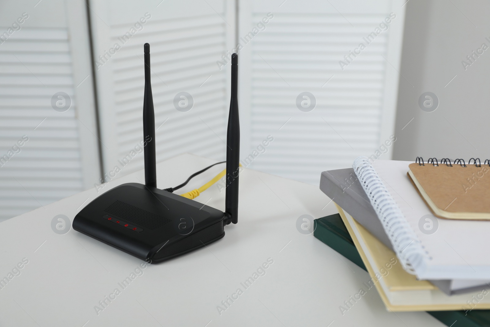 Photo of Modern Wi-Fi router on white table in room