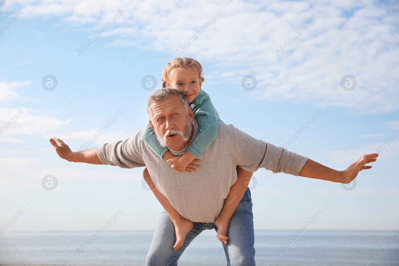 Photo of Little girl playing with grandfather on sea beach
