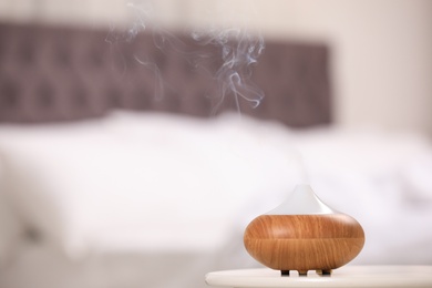 Photo of Modern essential oil diffuser on table indoors. Space for text