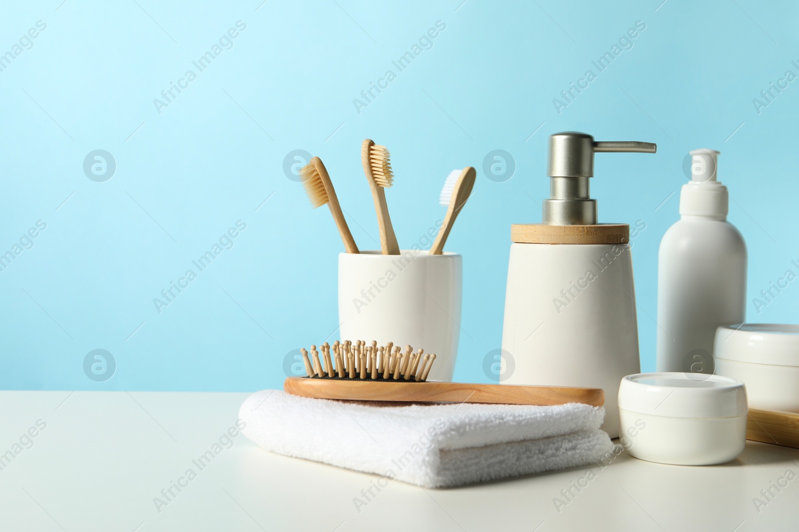 Photo of Different bath accessories on white table against light blue background. Space for text