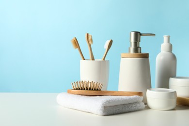 Different bath accessories on white table against light blue background. Space for text