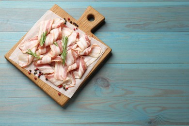 Slices of raw bacon and spices on light blue wooden table, top view. Space for text