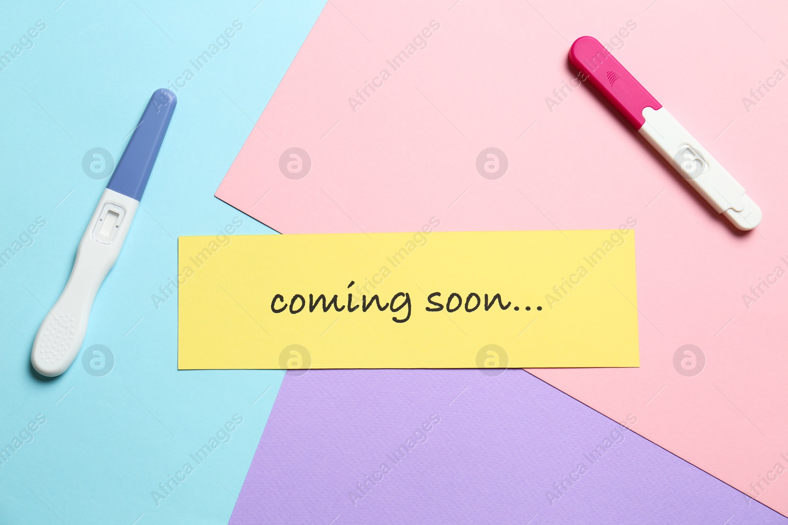 Photo of Card with words COMING SOON and pregnancy tests on color background, flat lay