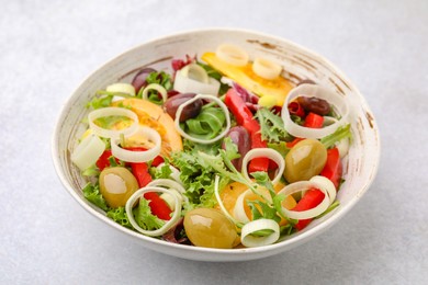 Photo of Bowl of tasty salad with leek and olives on light table