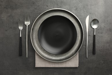 Stylish setting with cutlery and plates on black table, flat lay