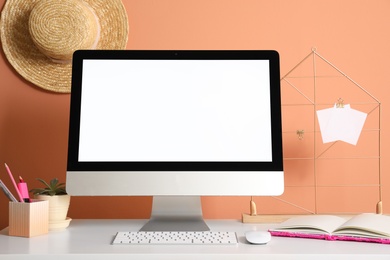 Photo of Comfortable workplace with modern computer on table near orange wall. Space for design