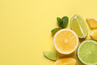 Fresh ripe lemons, limes and mint leaves on yellow background, flat lay. Space for text
